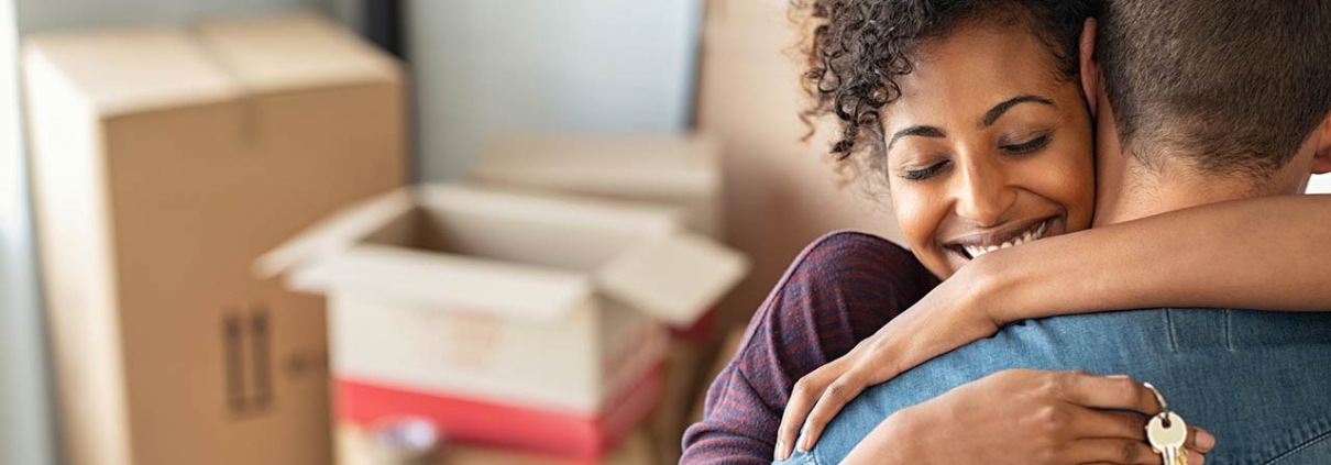 Woman holding keys from new home and embracing man