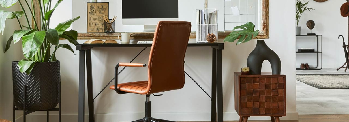 Creative composition of modern masculine home office workspace interior with black industrial desk, brown leather armchair, pc and stylish personal accessories