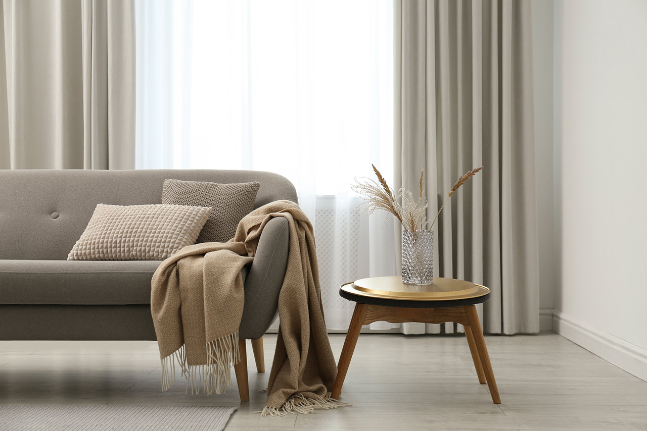 Grey sofa with pillows near window in stylish living room interior