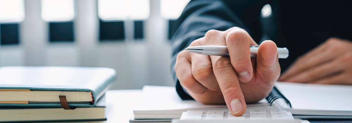 Businessman presses a calculator on a desk with notebooks