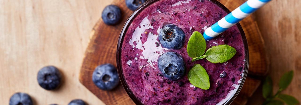 Glass of blueberry smoothie on wooden background from top view