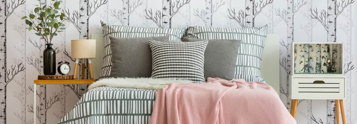 Feminine bedroom interior with forest inspired wallpaper and geometric bedding
