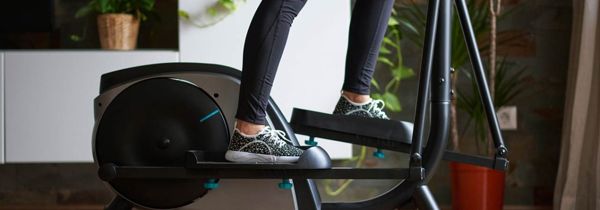 A womans legs training on smart elliptical trainer indoors at home in daylight with natural light