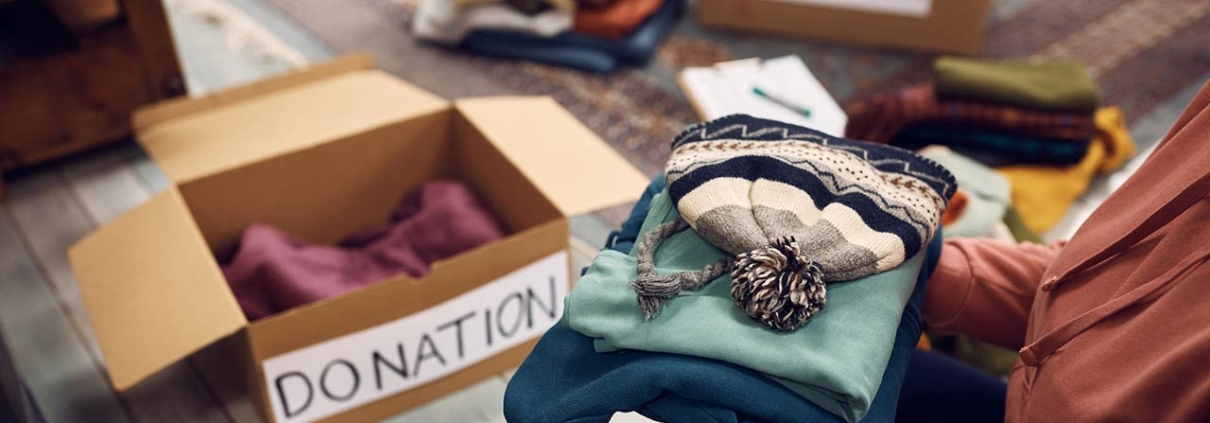 Close-up of woman packing boxes while donating her wardrobe for charity