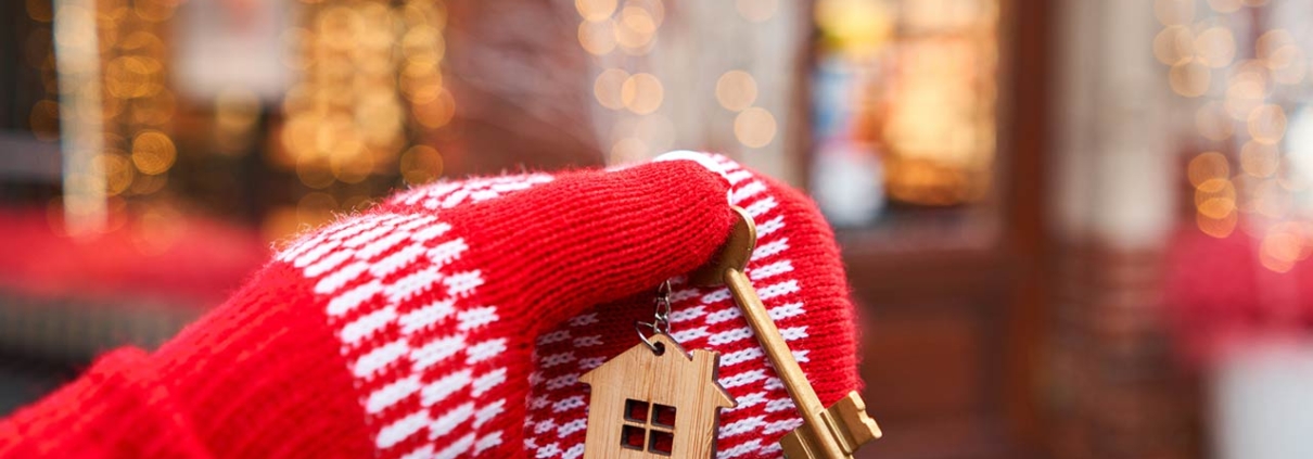 Hand in red mitten holding key with house shaped keychain