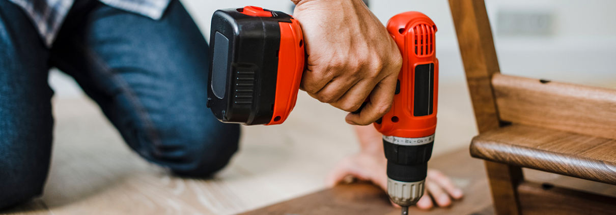 Man using hand drill to assemble a wooden table