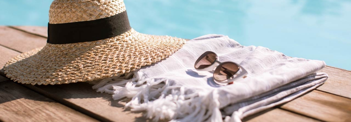 Sunglasses and straw hat on the wooden floor at the pool