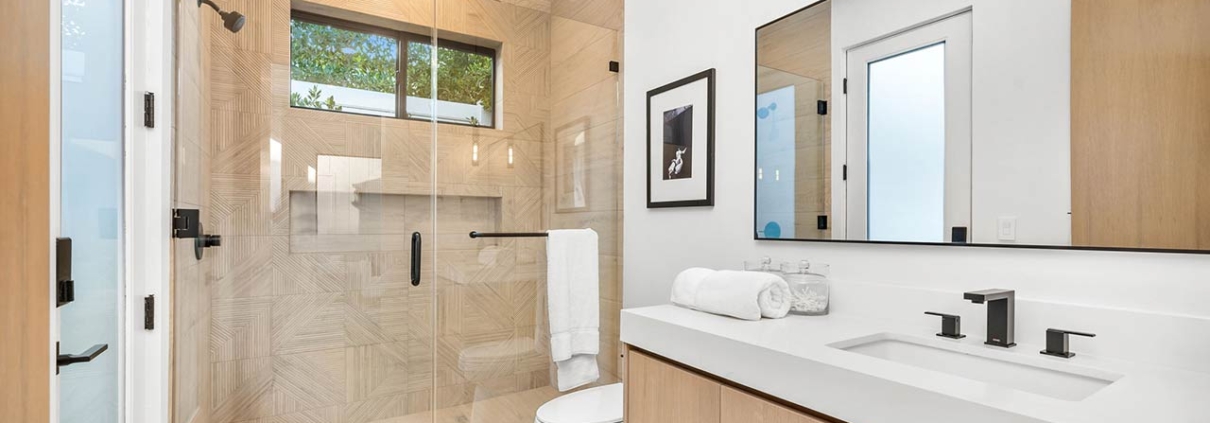 Modern bathroom with glass shower, wooden cabinets, and sleek fixtures in a bright, minimalist design