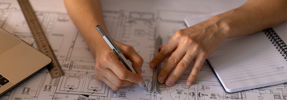Architect working on a construction project, drawing blueprints using a ruler and a technical pen