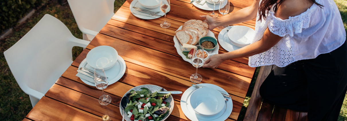 Top view of woman setting food on wooden table for housewarming party.